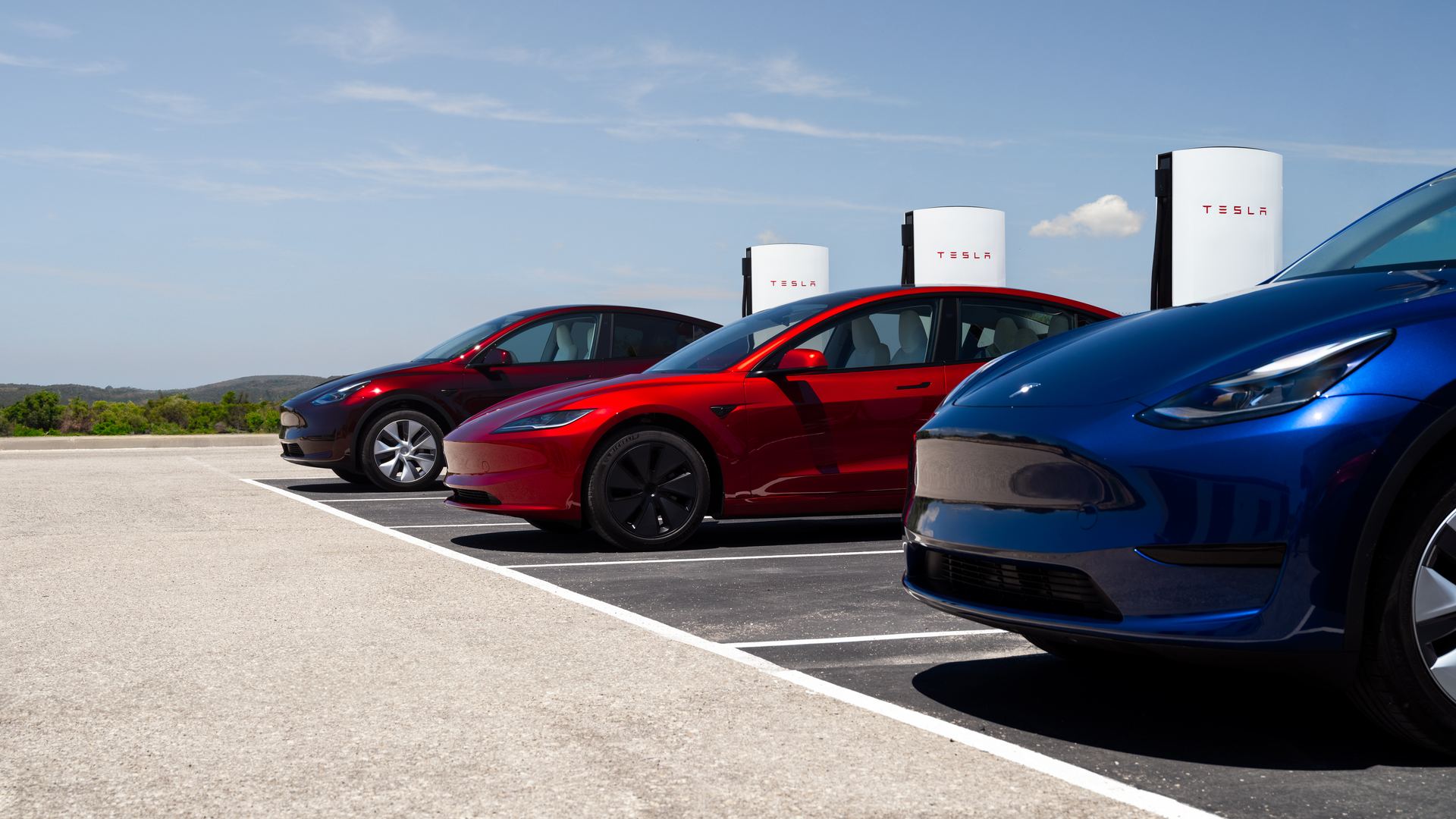 Row of Tesla vehicles charging at a Supercharger site